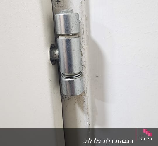 ציר דלת מתכת מותקן על משקוף לבן